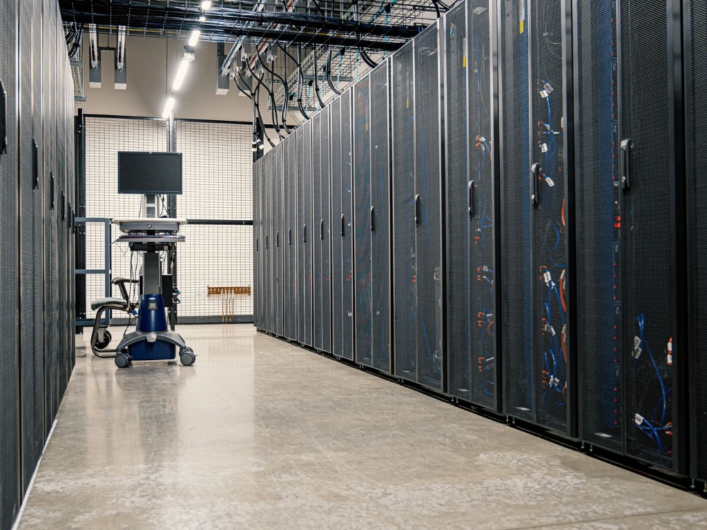 Allée d'un centre de données bordée de baies de serveurs fermées.